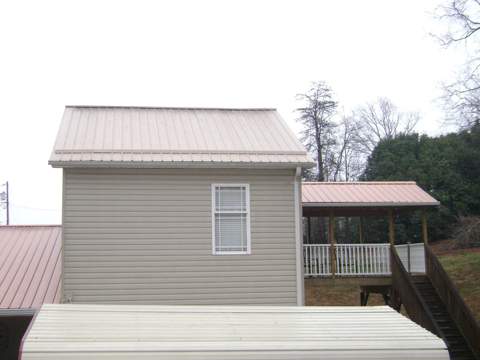 Tan metal roofs on a two story addition and attached porch, from a Roof Replacement job in Waltham